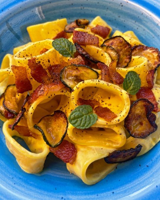 CALAMARATA CON CREMA ALLO ZAFFERANO E ROBIOLA, CHIPS DI ZUCCHINE E GUANCIALE