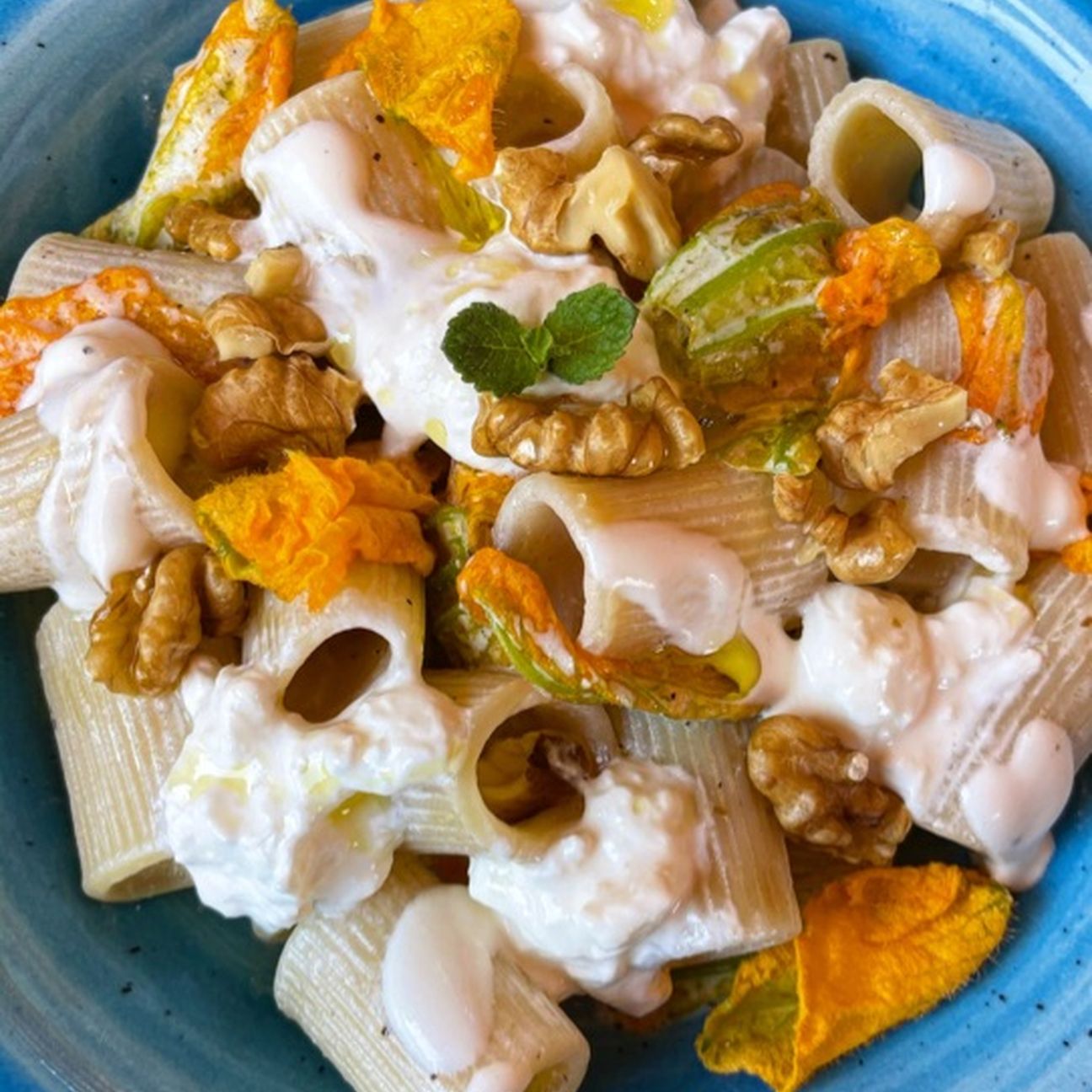 Mezze maniche con crema di burrata, fiori di zucca e noci