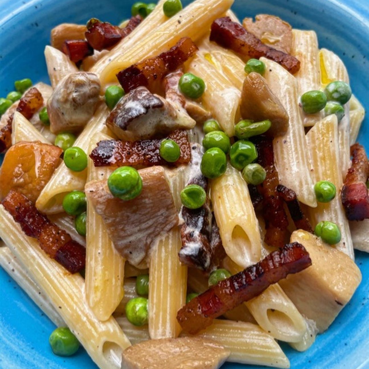 Penne con besciamella ai funghi porcini, piselli e pancetta croccante
