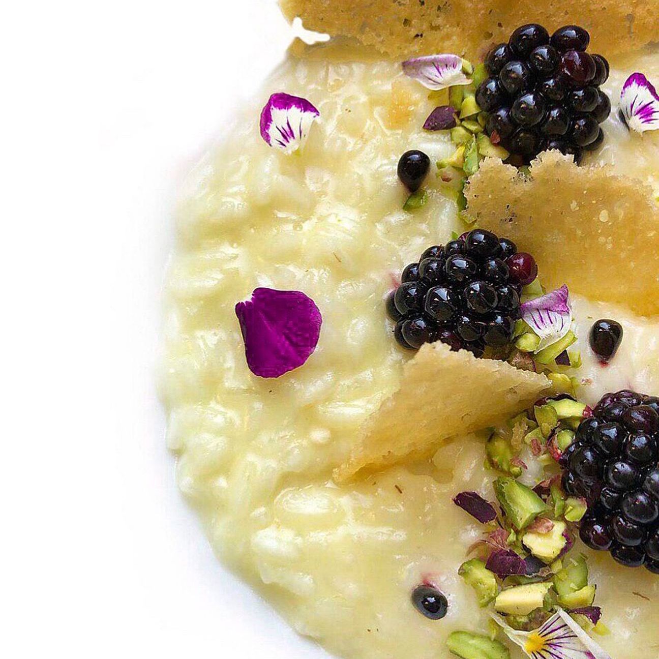Risotto al parmigiano con more, pistacchi e parmigiano.