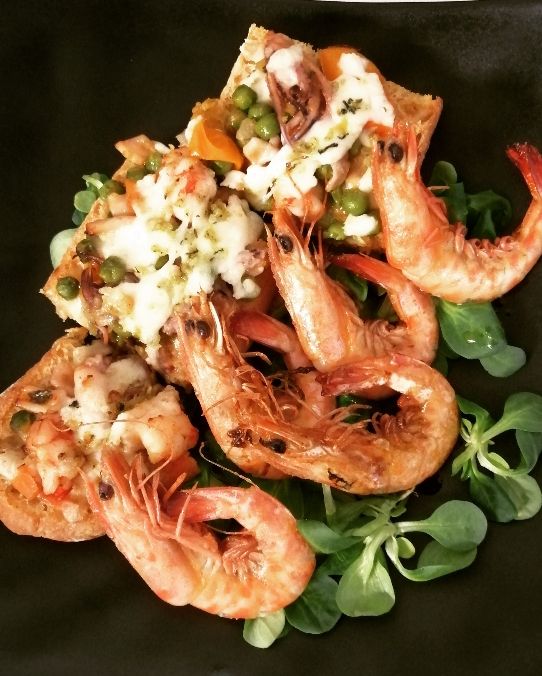 Crostone di pane con piselli, calamari e mazzancolle.