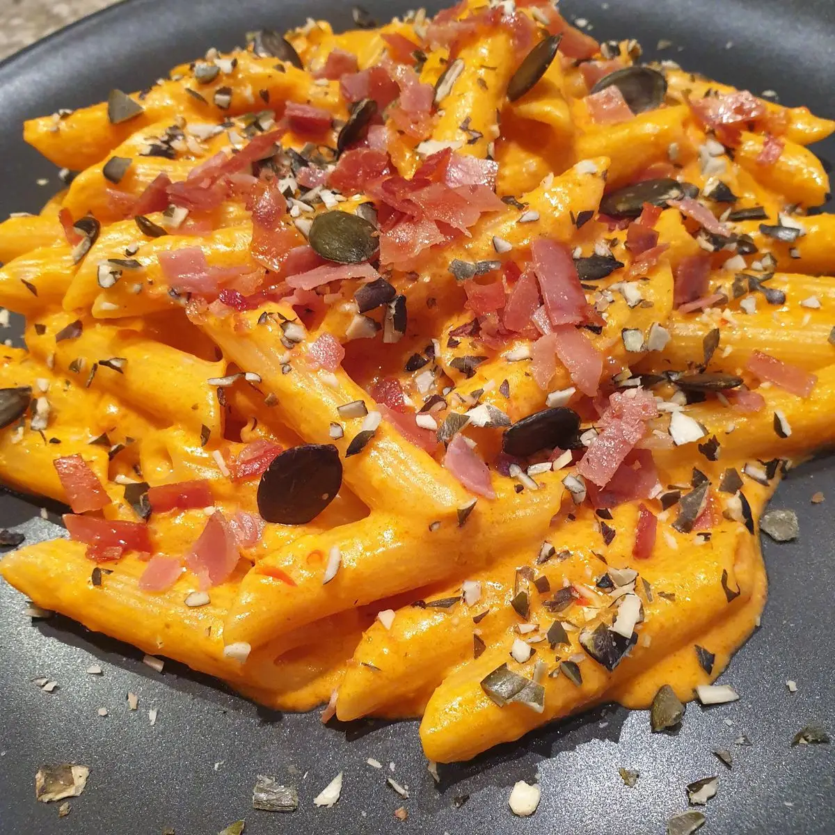 Ricetta Penne al pesto di peperoni e ricotta con prosciutto croccante e granella di semi di zucca tostati di Robertobabbilonia